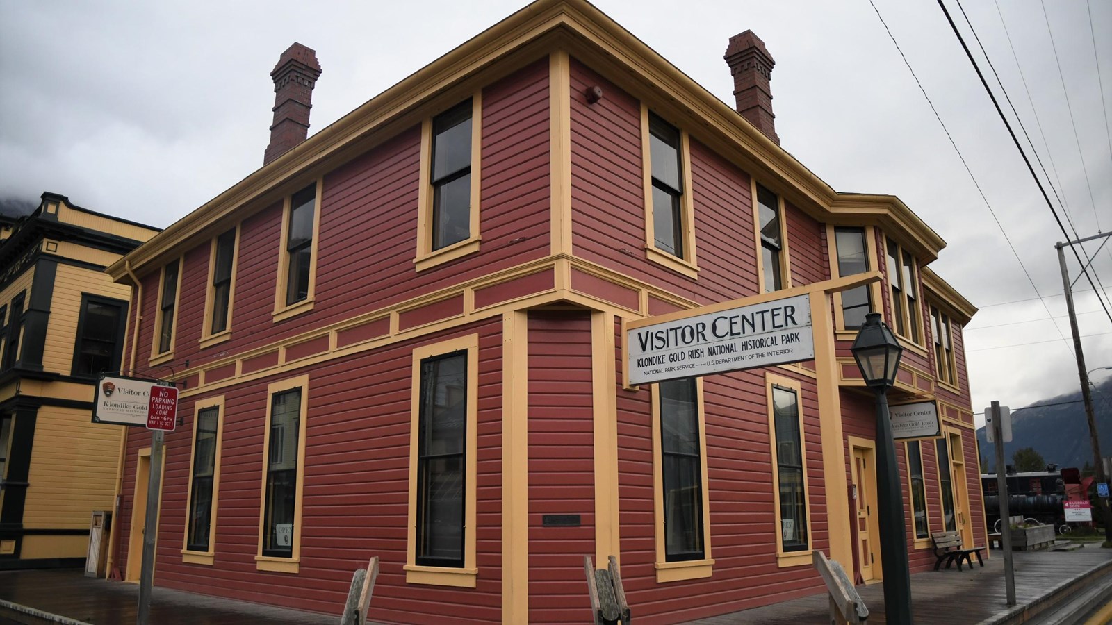 A historic two-story red building with yellow trim reads “Visitor Center.