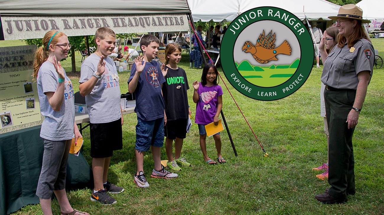 Children stand at attention with hands raised to become park junior rangers