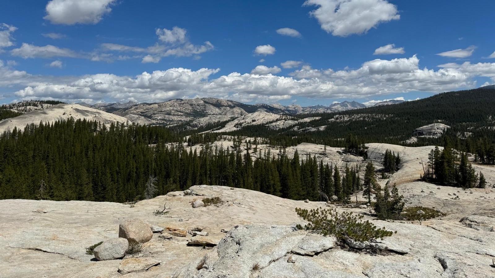 A granite surface in the foreground backdropped by distant rolling granite peaks