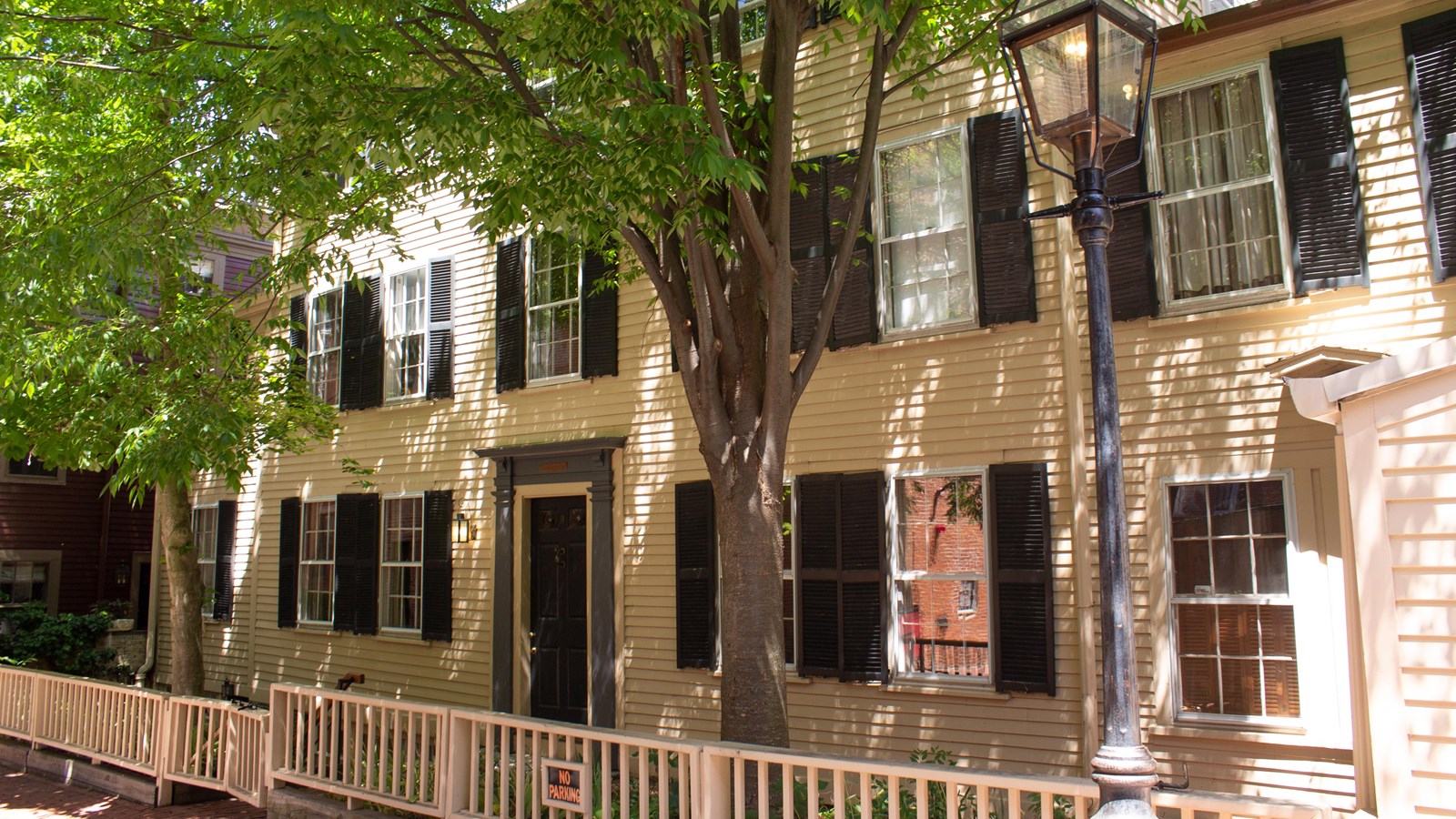 Series of dwellings with clapboard siding and yellow paint. Black shutters on windows.