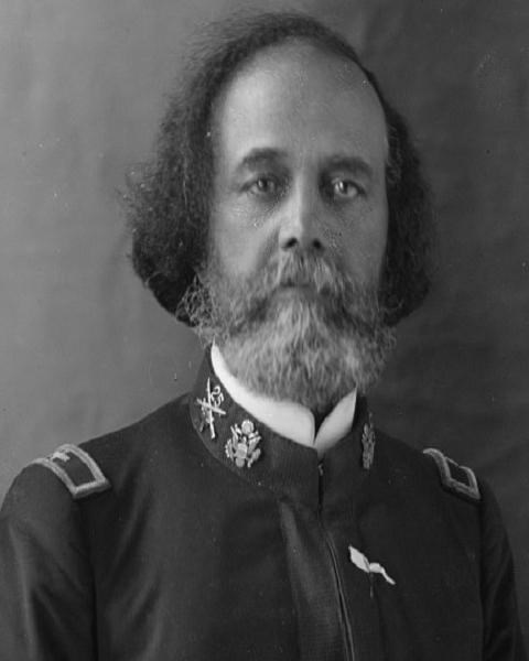 African American man in military uniform with an eagle and rifles crossed with a "25" pins.