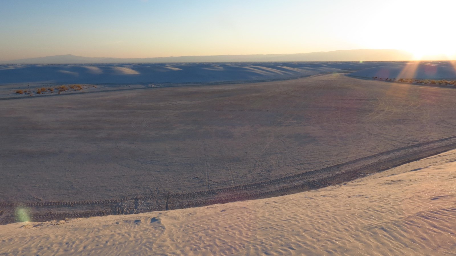 A large parking area surrounded by white gypsum sand dunes.