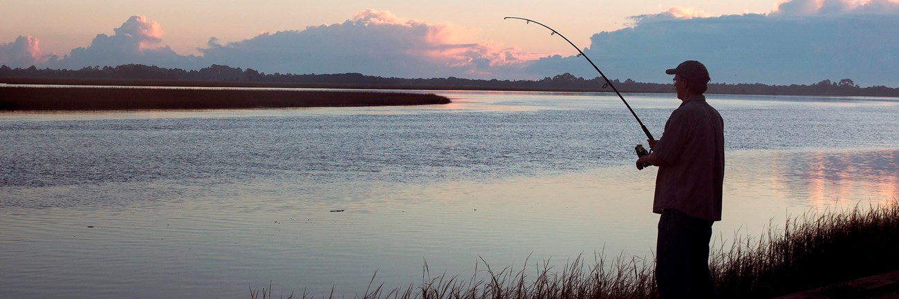 silhouetted angler fishing at dawn