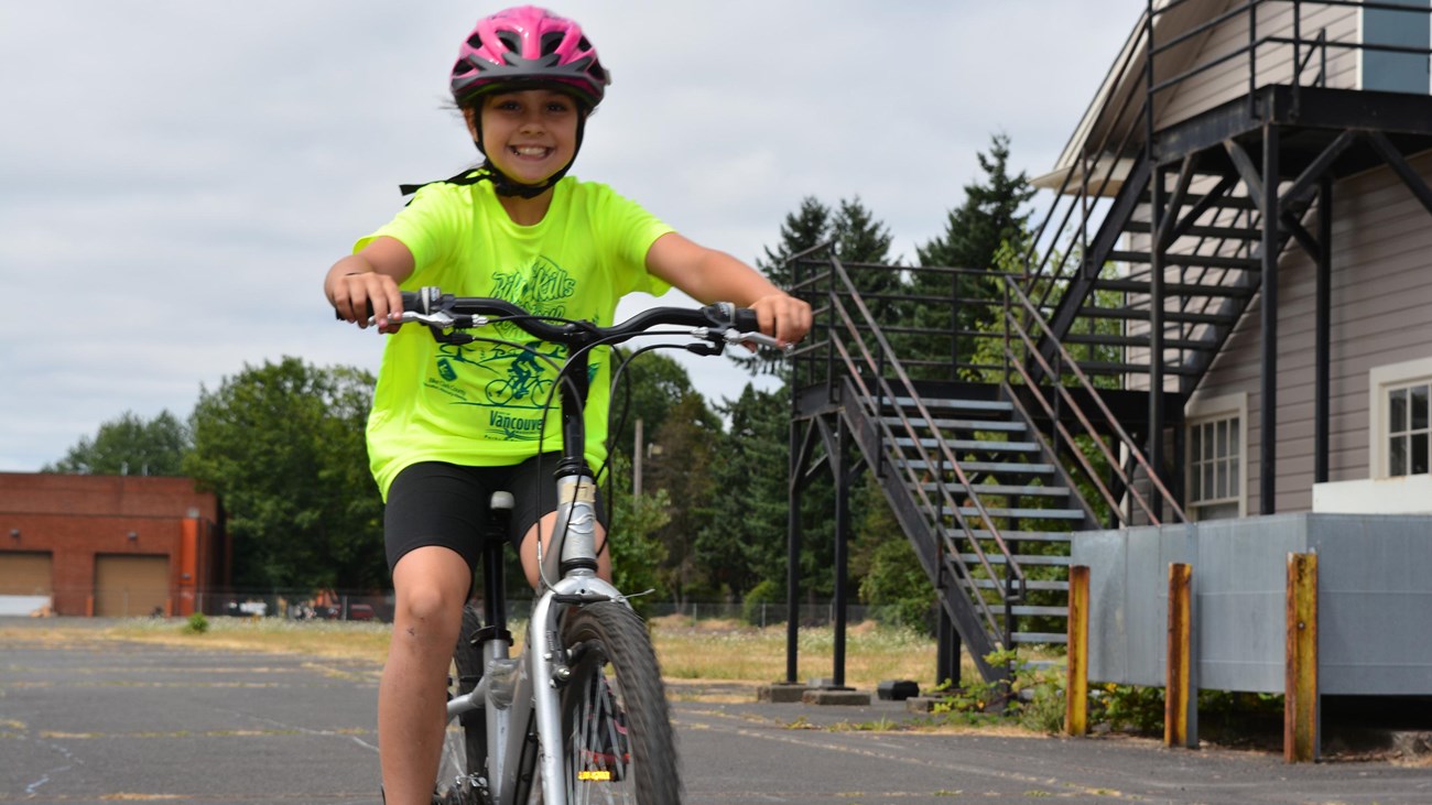 A child on a bicycle wearing a pink helmet.