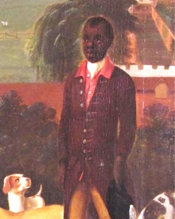 A brown colored man with short, black hair stands in a nice jacket, waiting patiently on something.