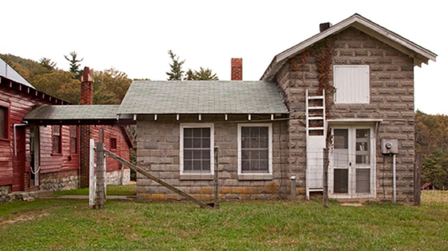 A gray stone building sits behind a large red barn
