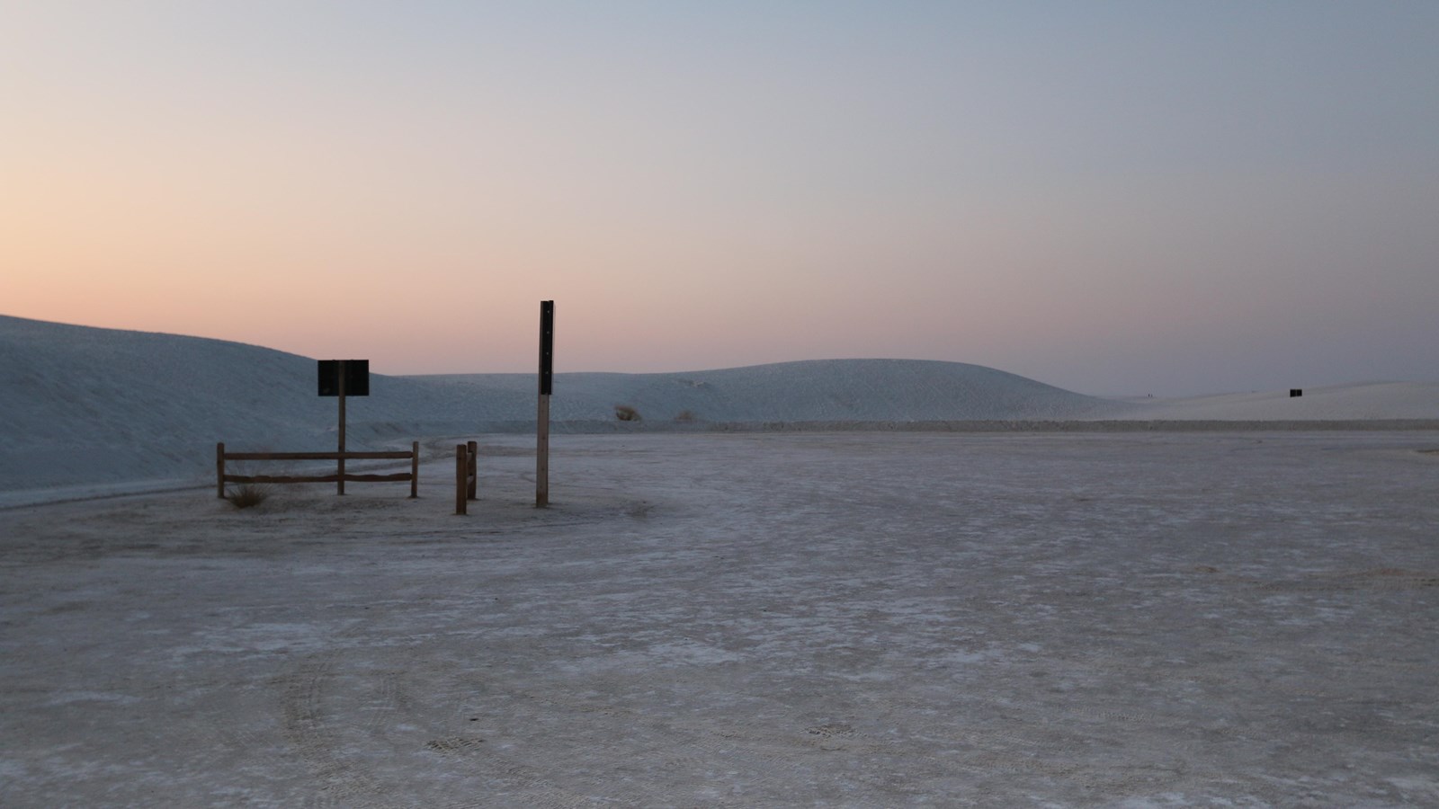 A large parking area surrounded by white gypsum sand dunes.
