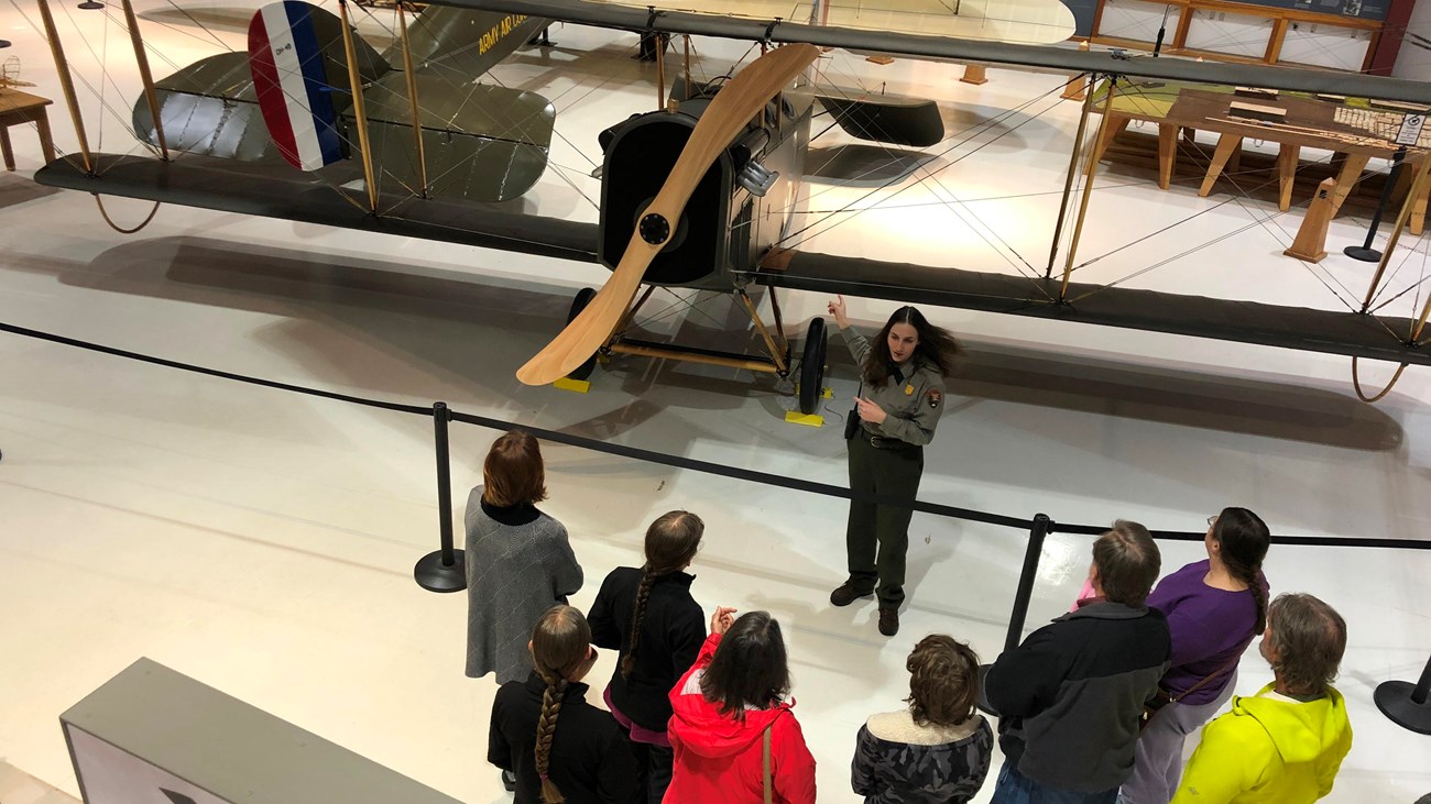 A park ranger talking about a biplane with a group of visitors inside Pearson Air Museum.