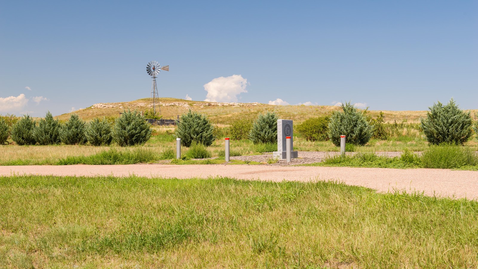 A rectangular gray monument stands right of center in this image, behind several red-tipped posts.