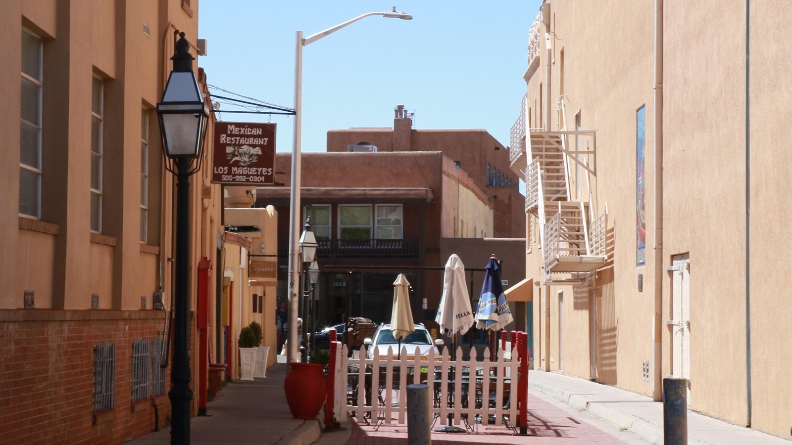 View down a narrow alley between two tall stucco office buildings.