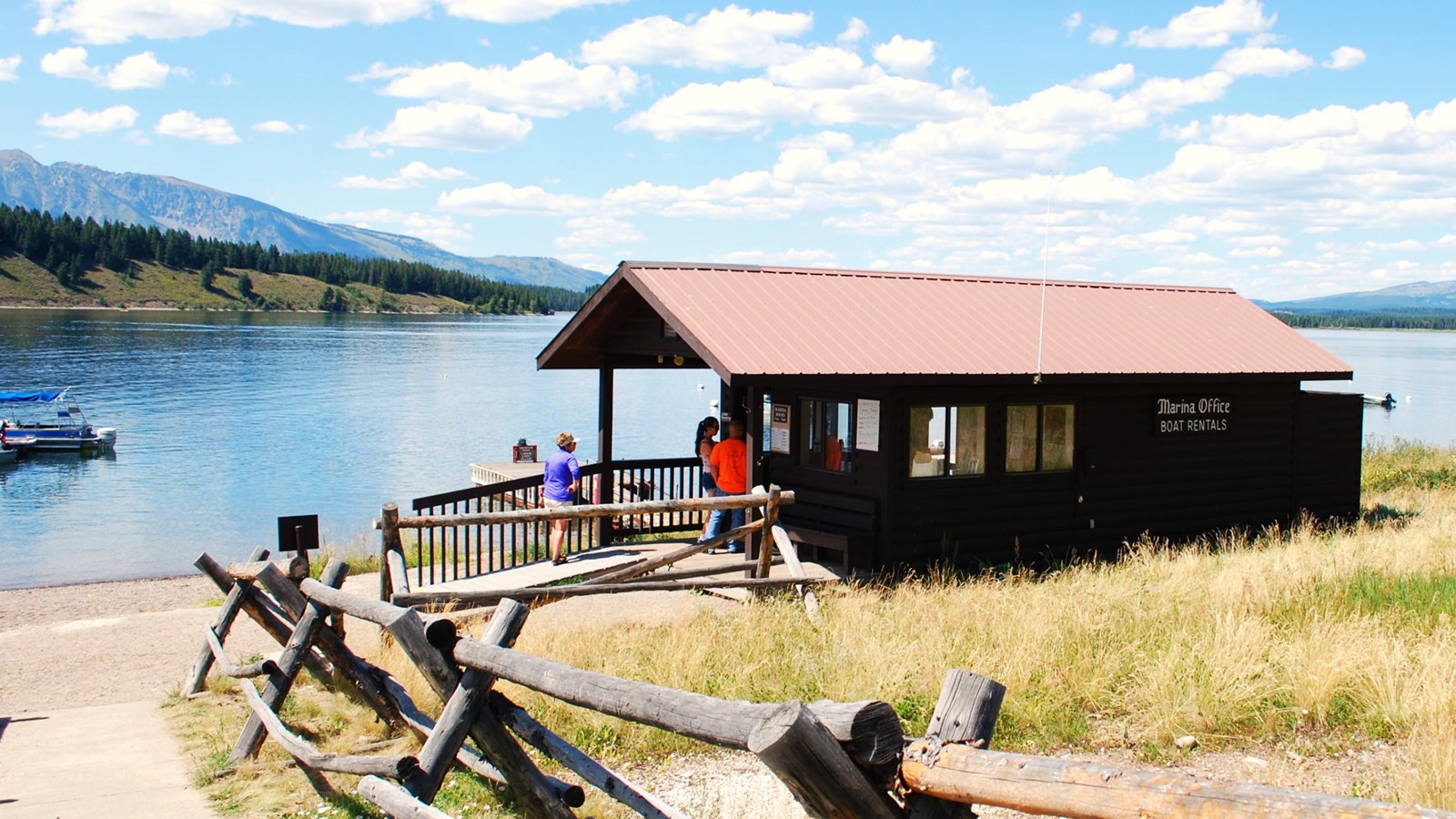 The marina with people outside and Jackson Lake Lodge with boats in the background.