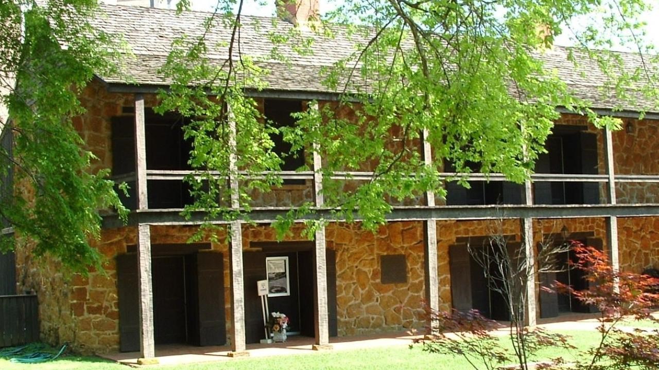 A two-story building with two chimneys and a stone exterior.