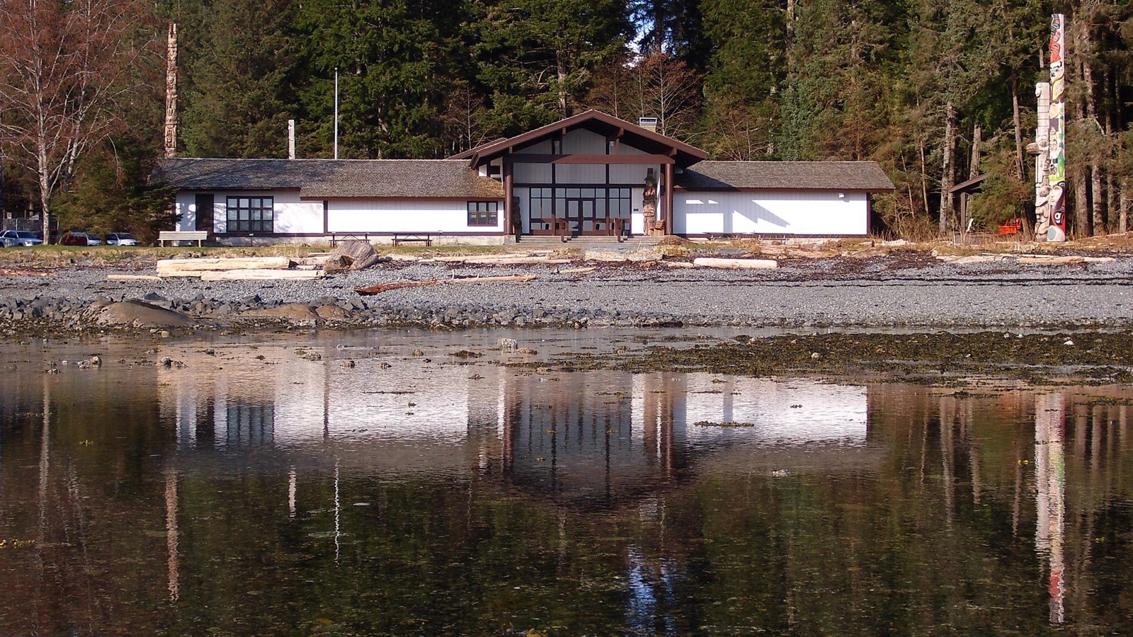 The covered porch of the visitor center. The building is reflected in the water in front of it.