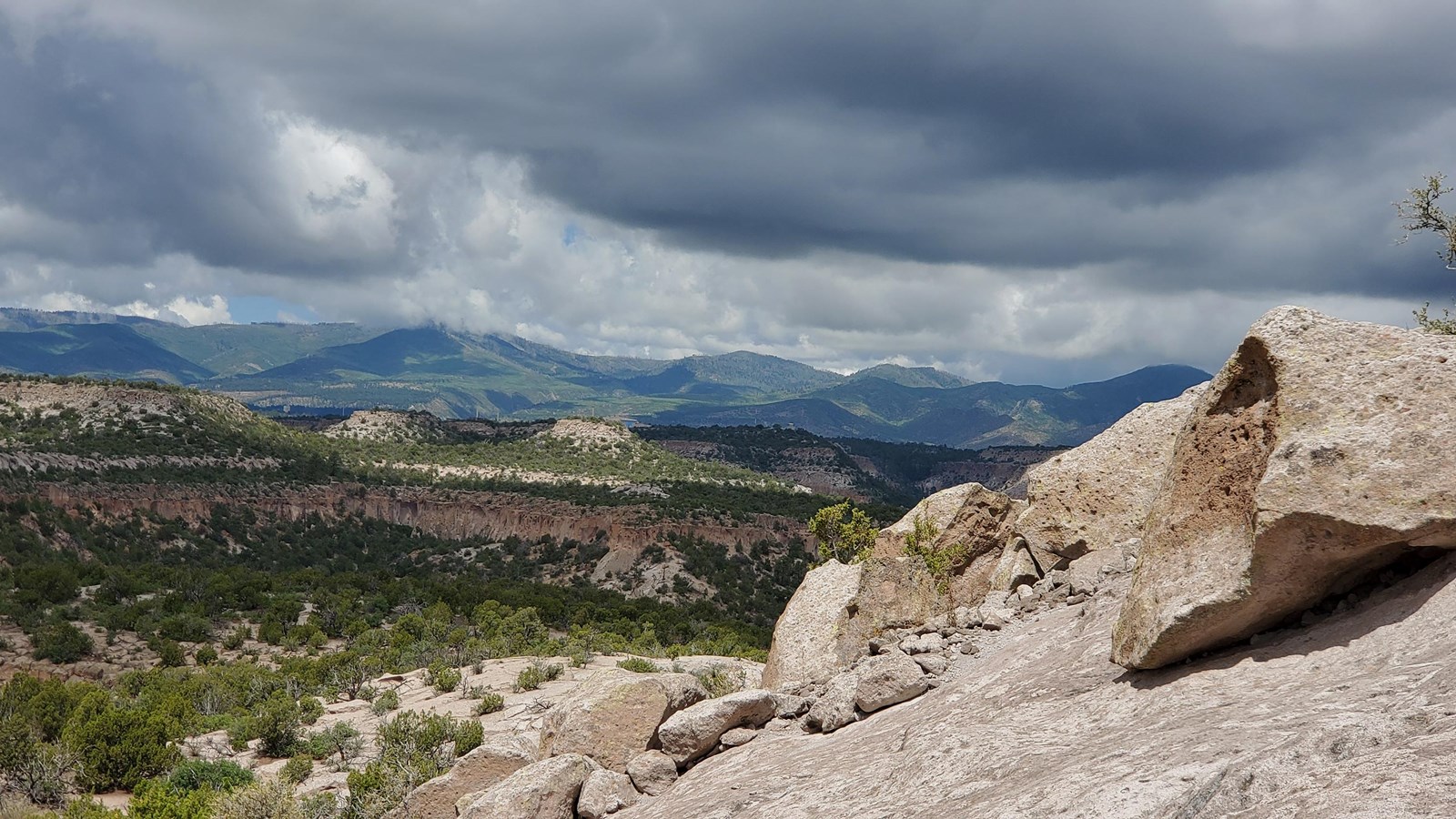 pale rocks in the foreground with green mountains in the distance and cloudy skies