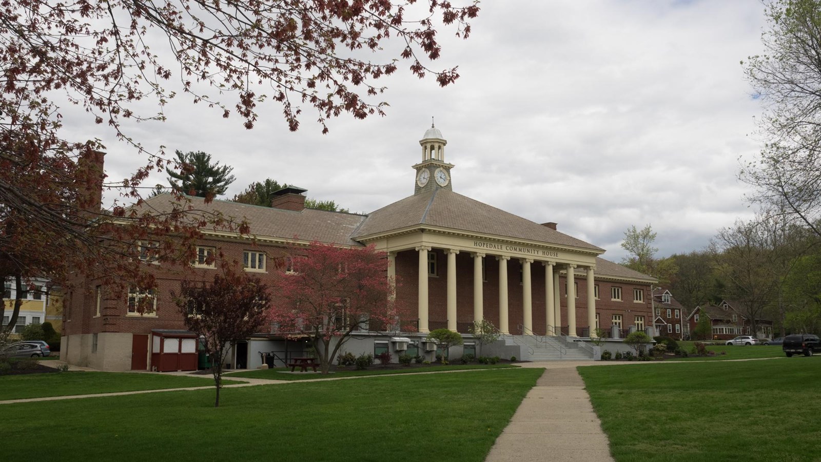 Large brick building with columns stands at the end of a grassy field