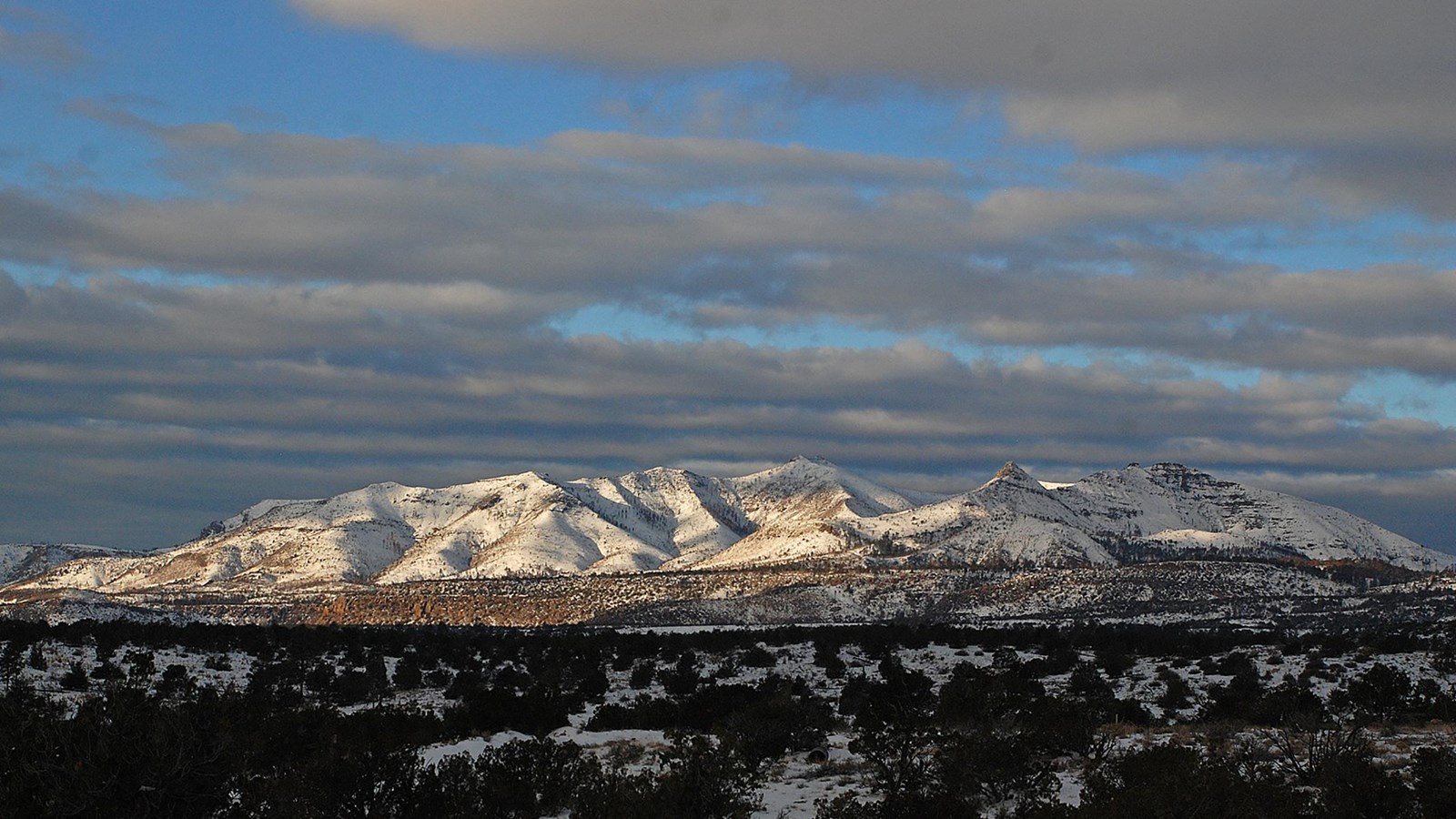 snowy mountains in the distance with broken clouds in a blue sky