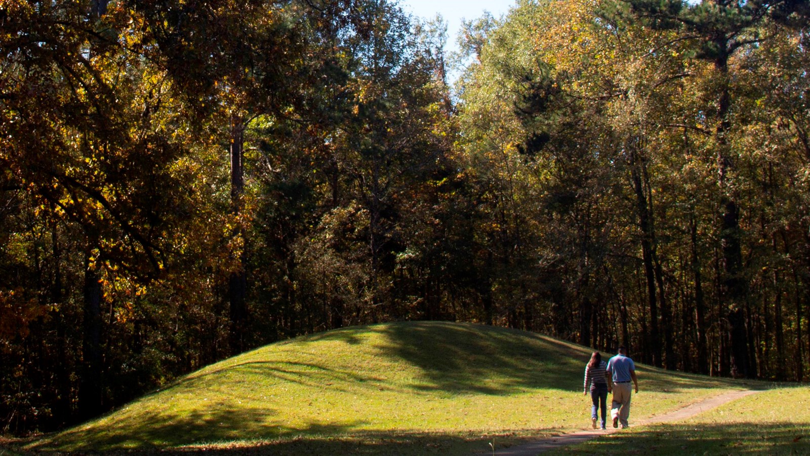 Visitors walking on paved trail passed Bynum Mounds on the left