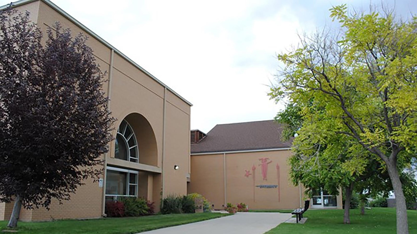 A large, light brown building surrounded by trees.