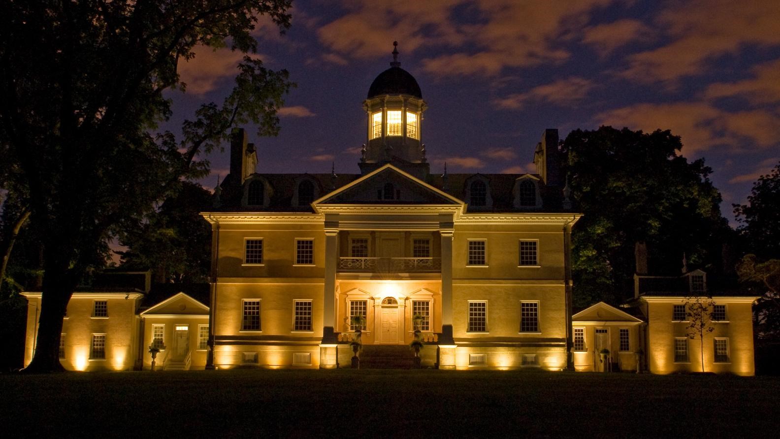 The Hampton mansion lit up at night.