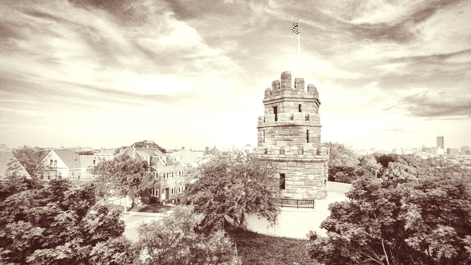 3-story stone monument that looks like a stacked English tower. U.S. Flag flies from the flagpole.