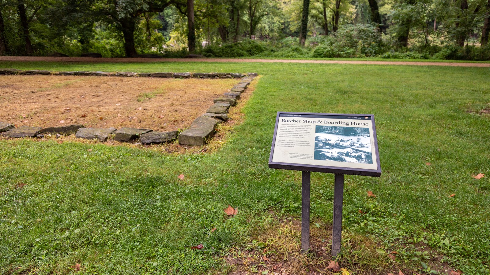 A small exhibit panel in front of a rectangular stone foundation.