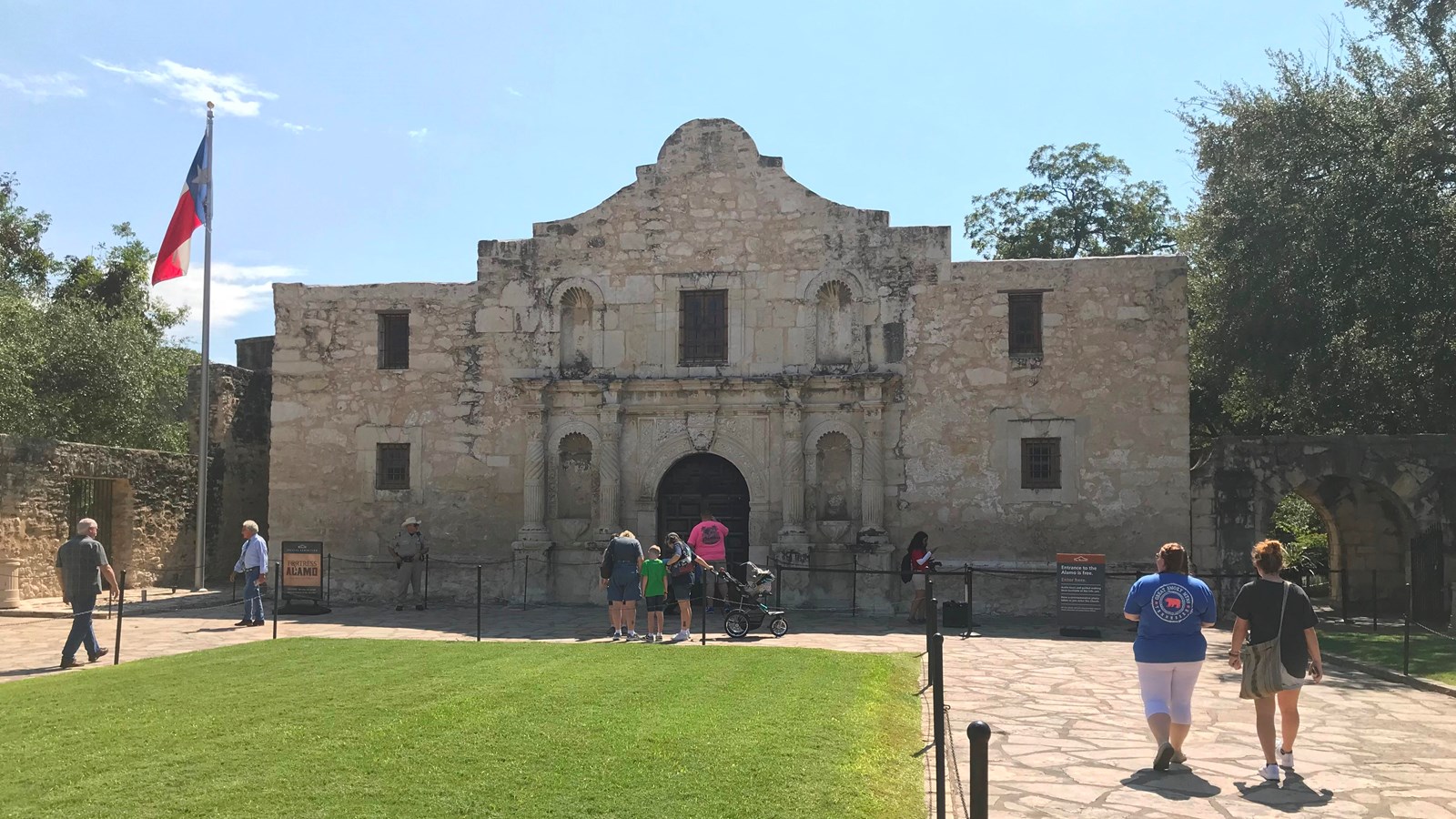 A historic spanish-style mission with a large grass field in front.