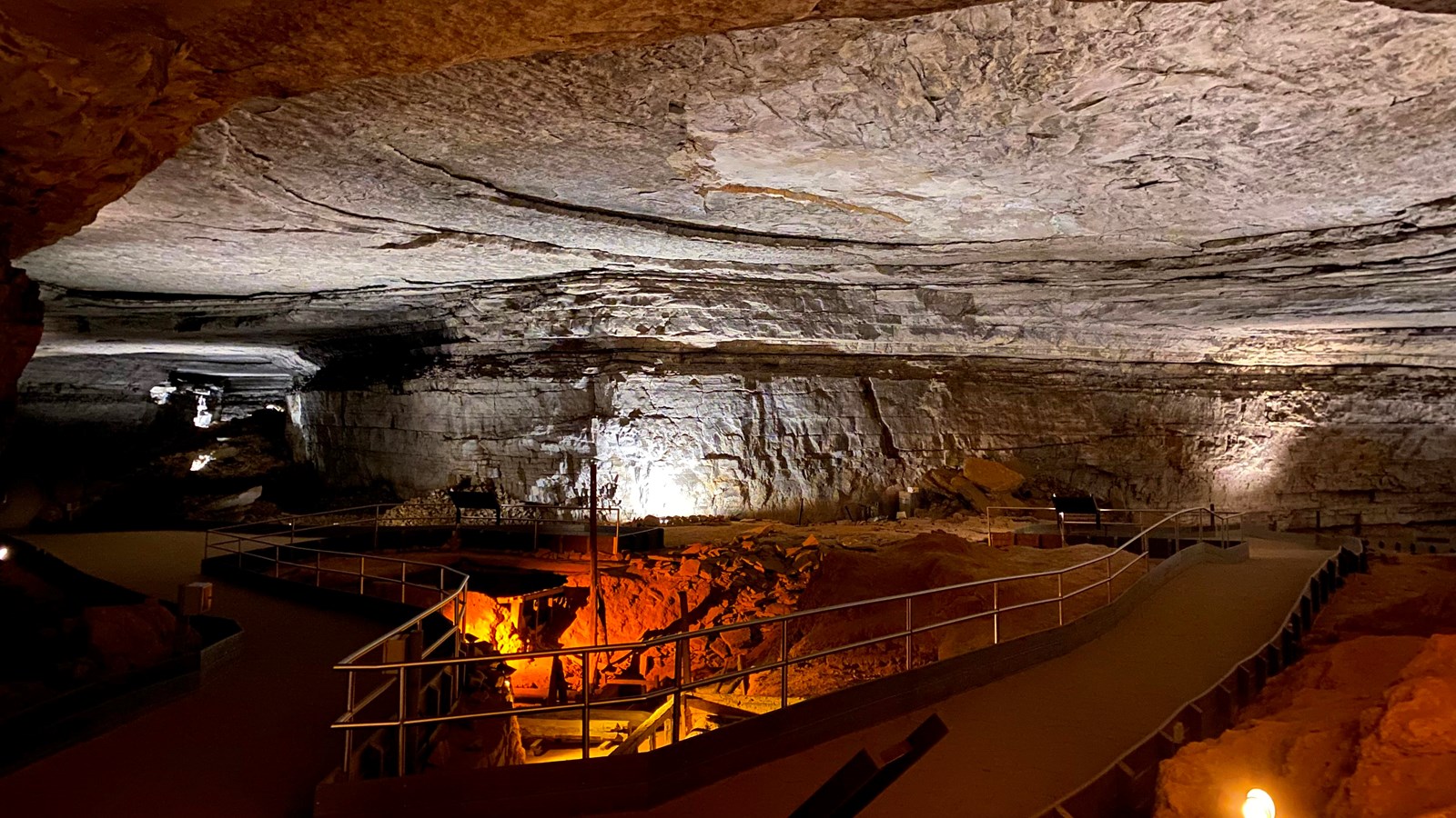 A large cave room with trails going off to the left and right. 