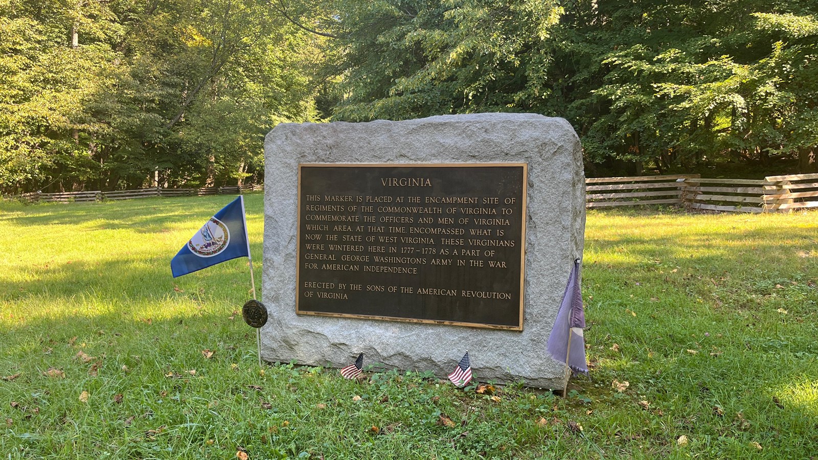 A monument of pale, rough-hewn stone containing a bronze plaque.