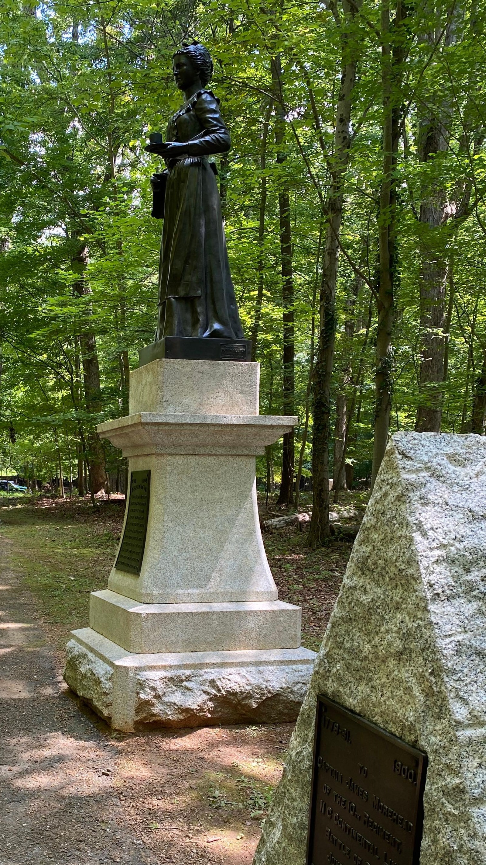 Monuemts include a stone shaped like a tent, and a statue of a woman holding a cup and saucer.