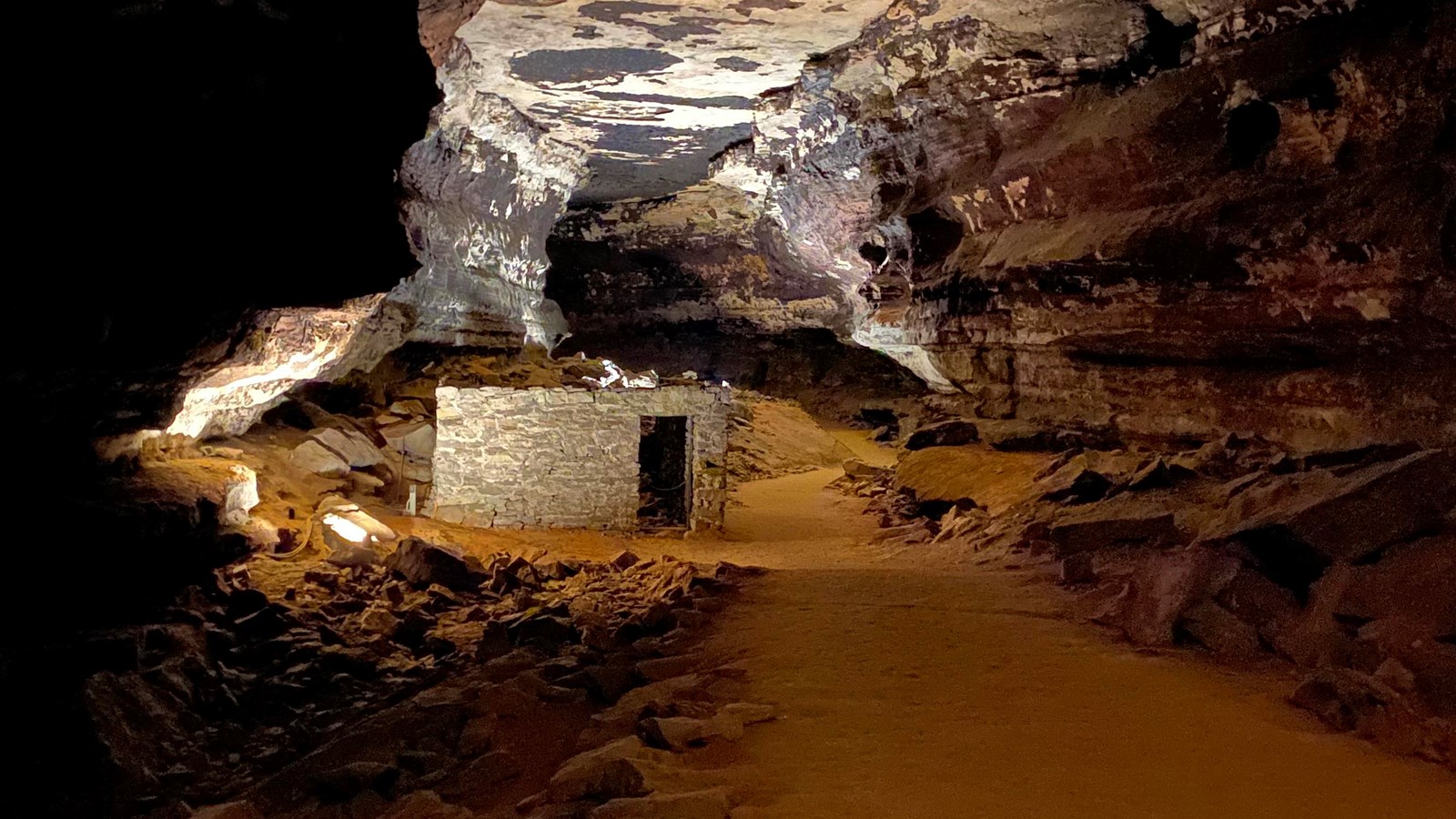 A rectangular stone building inside of a cave passage. 
