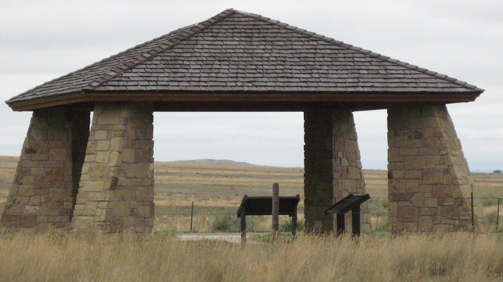 Stone pillared kiosk with information panels and a wood roof