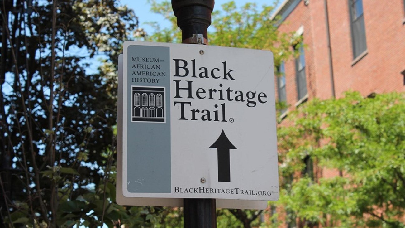 A white square sign on a lamp-post that states 