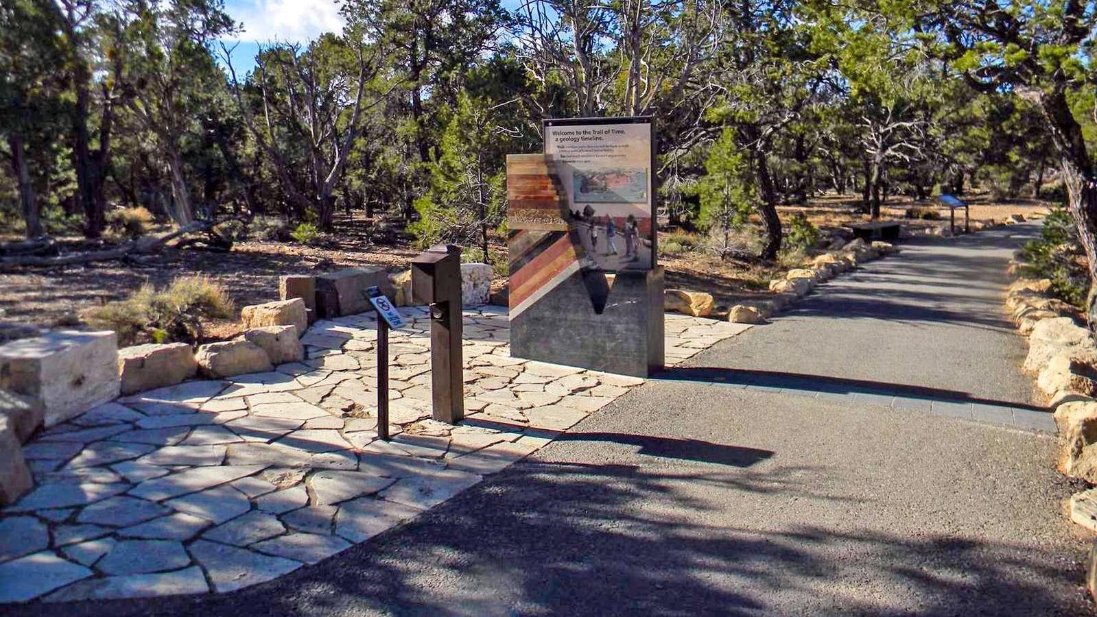 Along a paved footpath, flagstone slabs and a stone monolith mark the start of a geologic timeline,