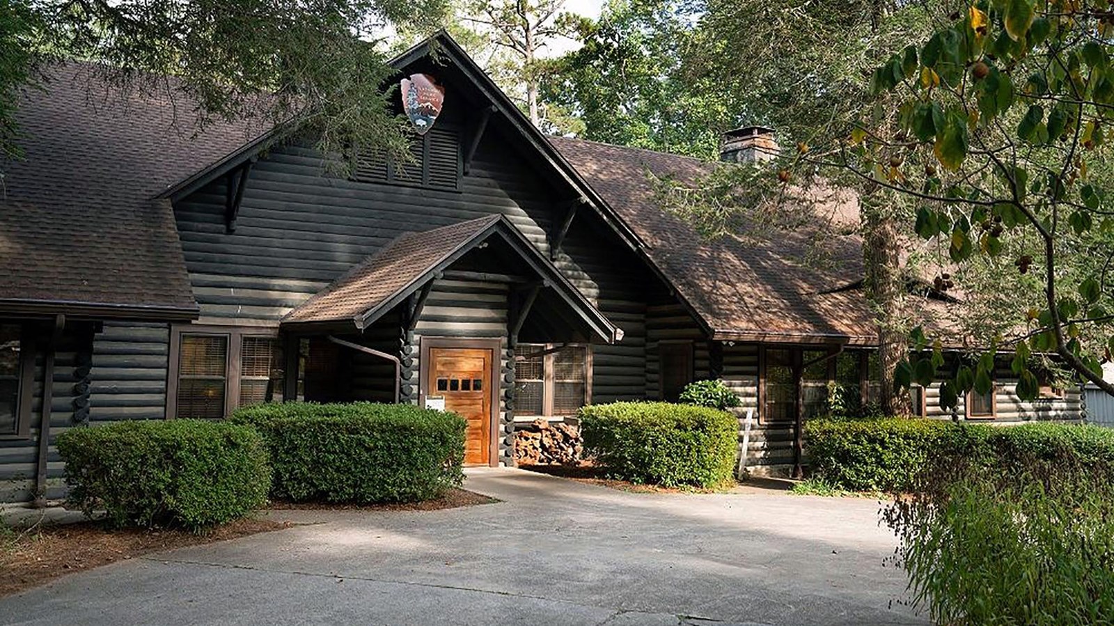View of Adirondack style building from the outside with steeply pitched roof and walls made of logs.