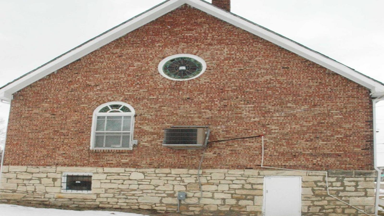 A one-story brick church can be seen in the center of the image. There is snow visible on the roof.