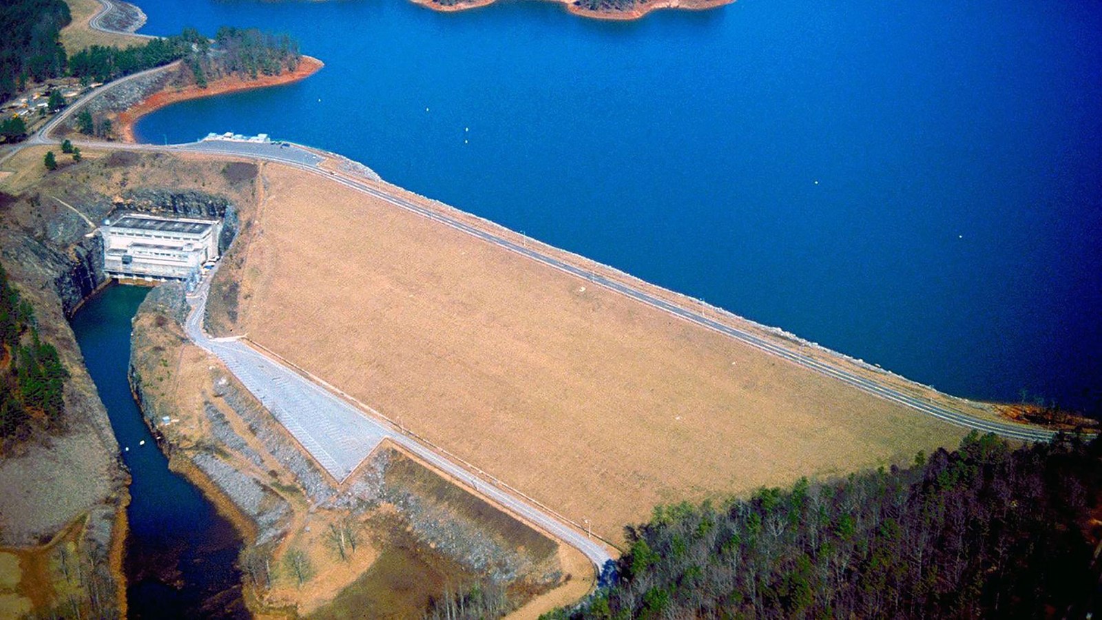 Aerial photo of dam looking at the downstream face of the dam with Lake Lanier in background