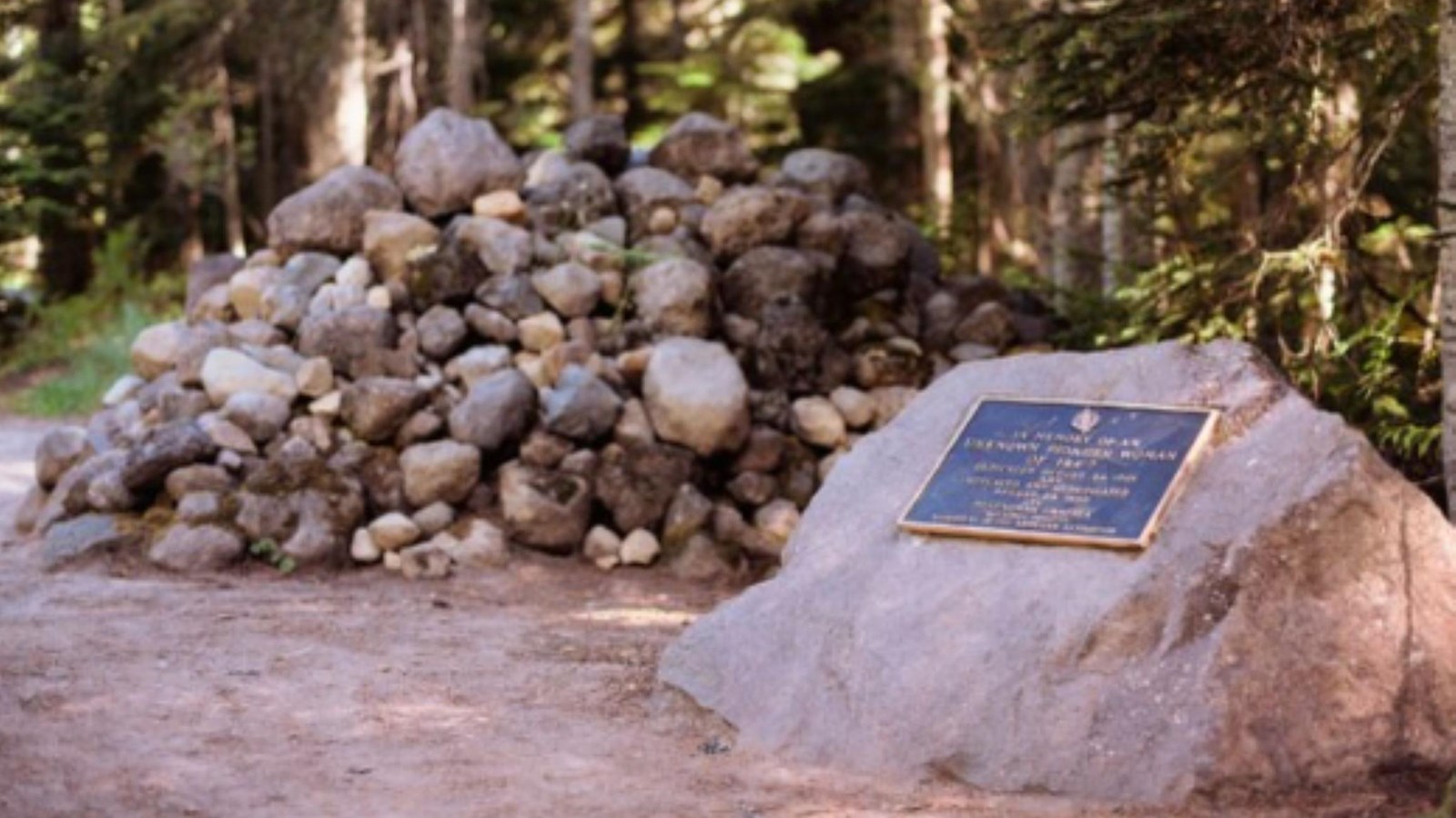 A rock monument sits next to a pile of rock in a forest.