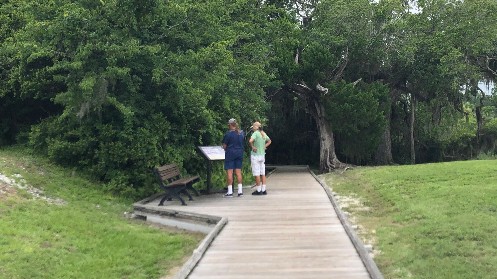 Boardwalk path, two visitors stand in front of wayside five.