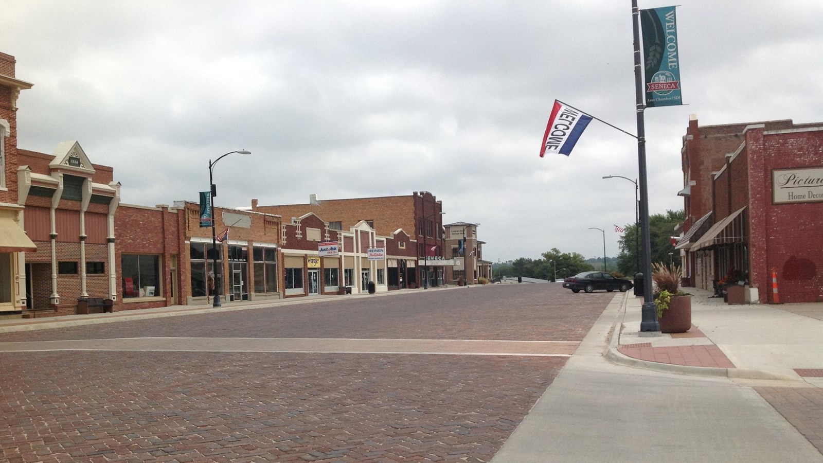 A bricked road leads through a historic downtown, lined with redbrick buildings.