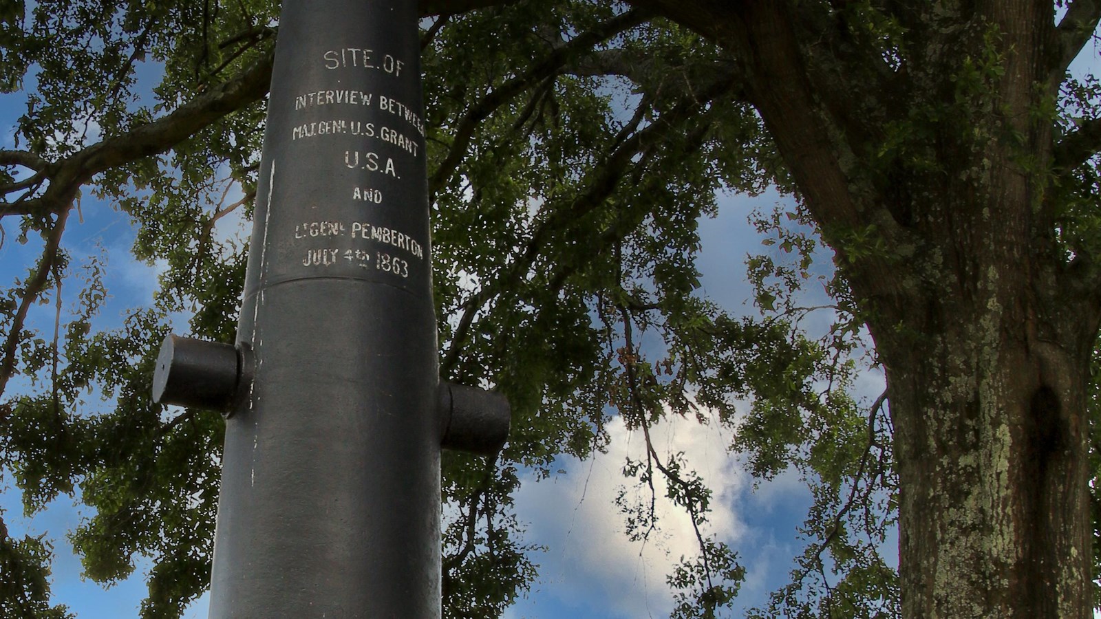 A vertical black cannon on a green grassy knoll commemorates the surrender interview site.