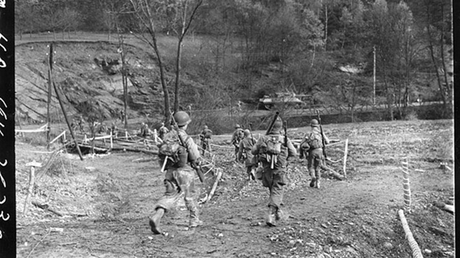 Black and white photo of uniformed men walking on a dirt path