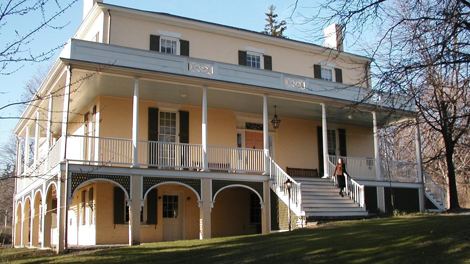a three-story painted brick house with wrap-around porch.