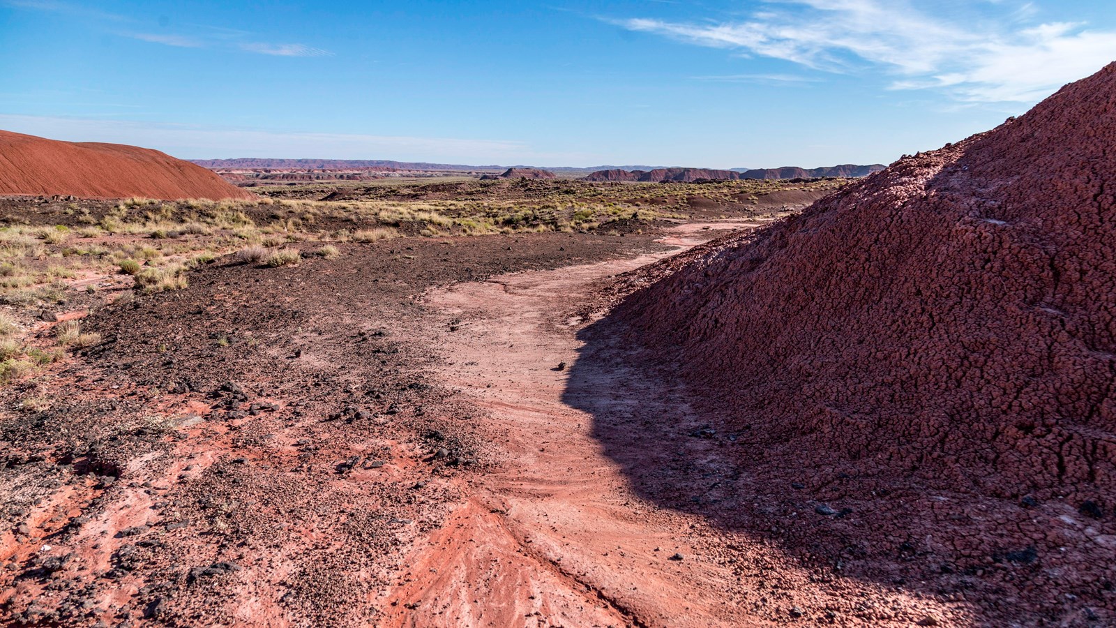 Badlands opening onto the plain with blue sky above