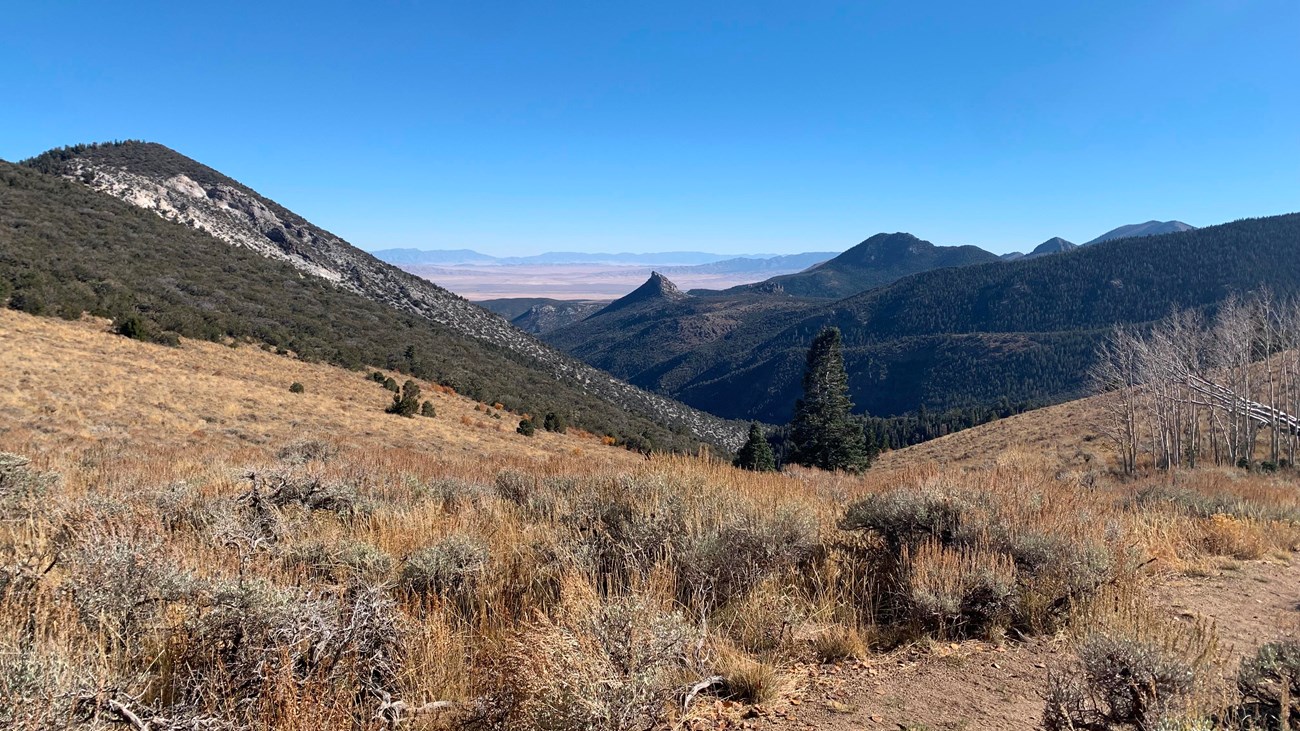 Brown and green sagebrush extends to mountains, a valley behind them, and another distant range.