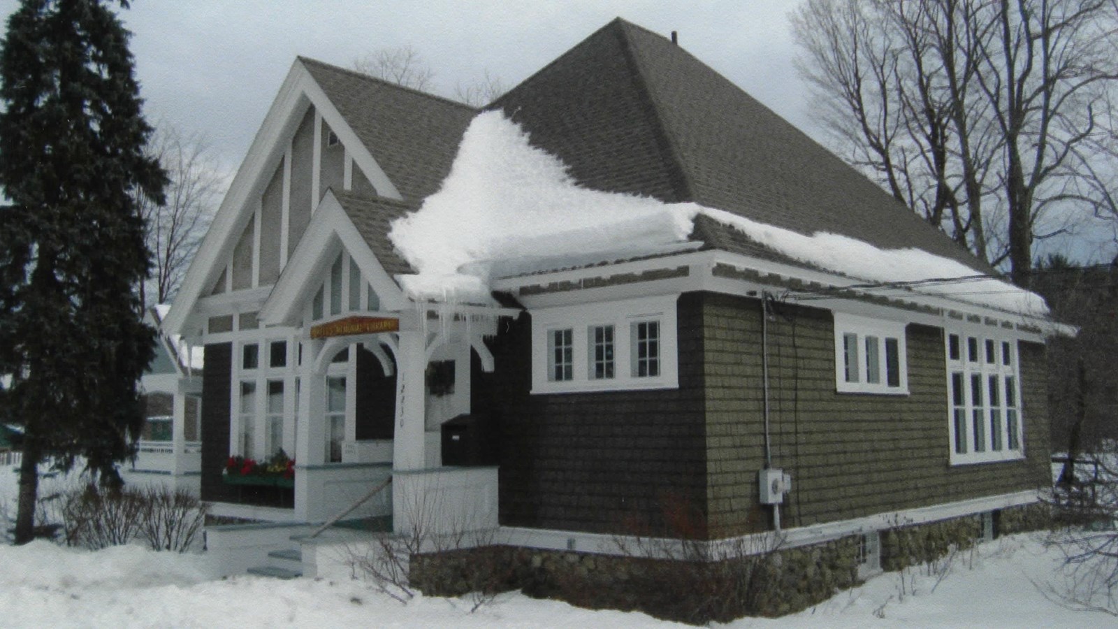 Snow-covered library with pine trees in background