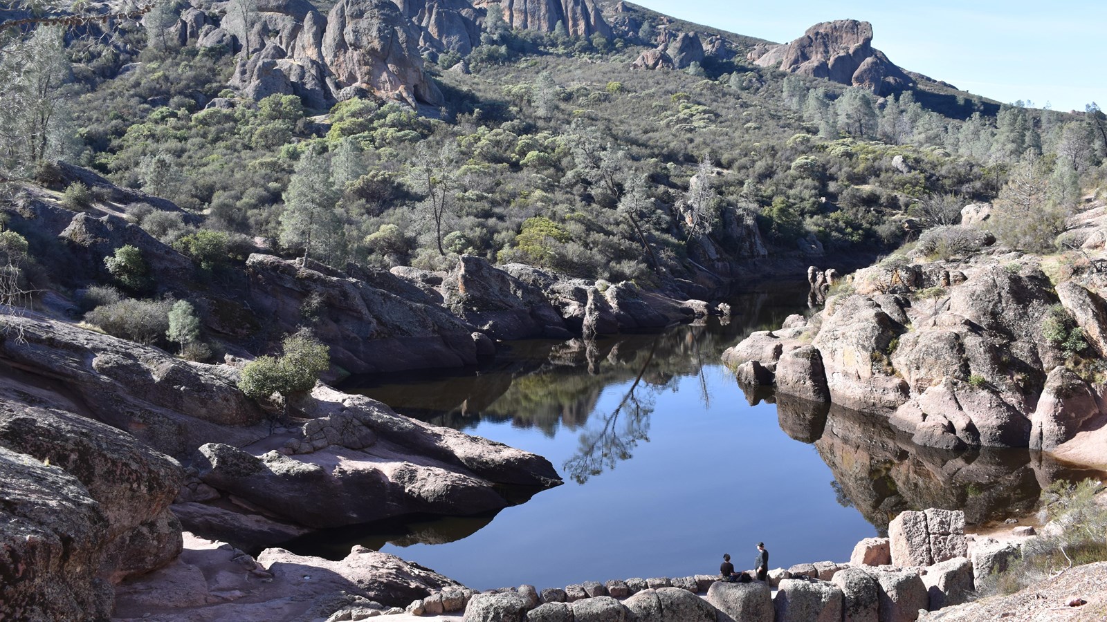 A view of the reservoir filled with water, surrounded by jagged rock formations on all sides.