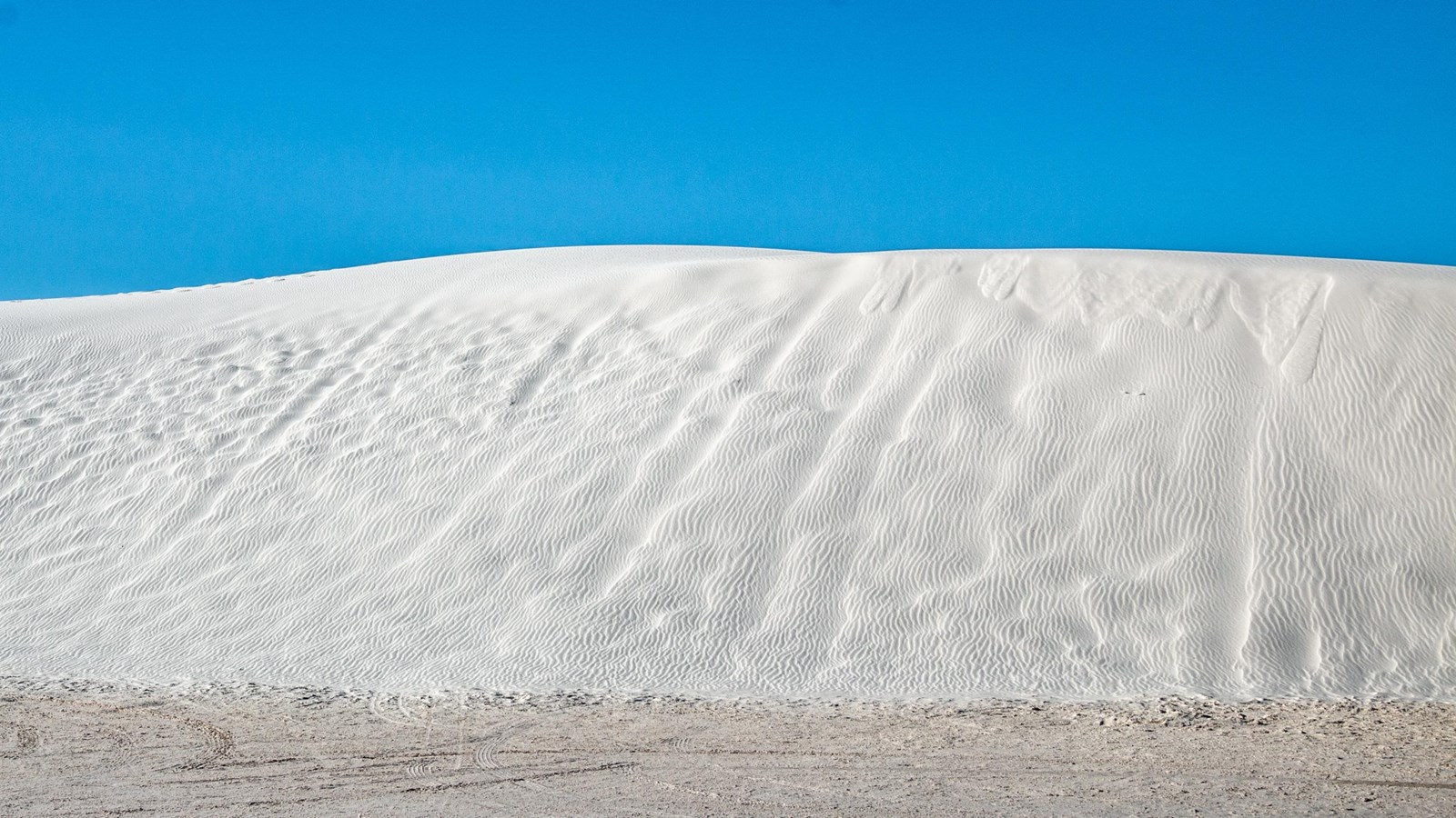 White sand dunes with a blue sky background.