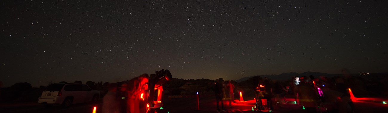 telescopes illuminated red beneath a star-filled sky