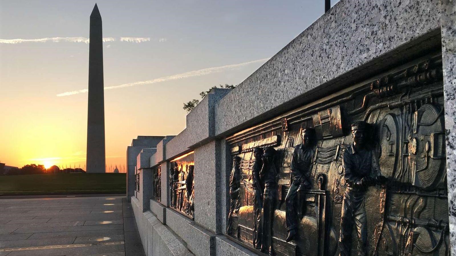 A bas-relief panel depicts men in a submarine. Sun rises behind Washington Monument in background.