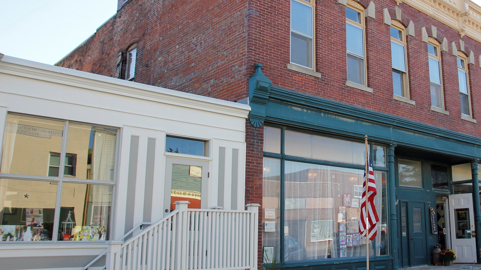 A brick commercial building has two stories and green and cream gingerbread trim.